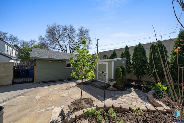 view of patio with a storage unit, a gate, fence, and an outbuilding