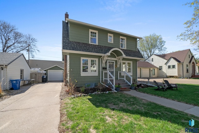view of front of property with roof with shingles, fence, a front lawn, a detached garage, and concrete driveway