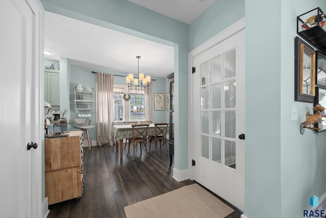 interior space with baseboards, a notable chandelier, and dark wood finished floors