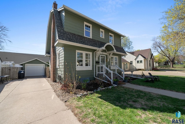 view of front of home with a shingled roof, a front lawn, a garage, a chimney, and driveway
