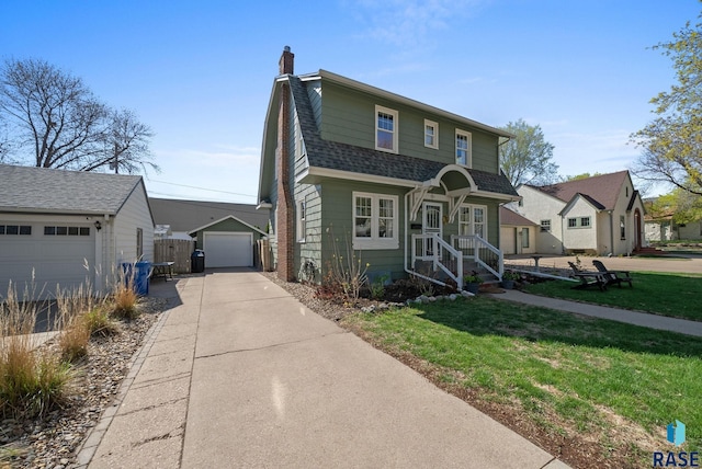 view of front of home featuring a chimney, roof with shingles, a detached garage, an outdoor structure, and a front lawn