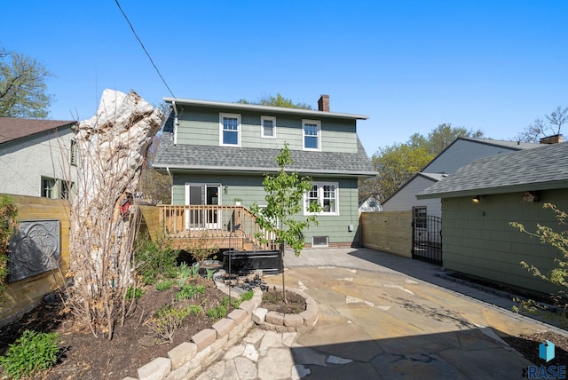 rear view of property featuring fence, a patio, a chimney, a gate, and a shingled roof