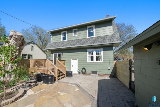 back of property with fence, a patio, a shingled roof, and a deck