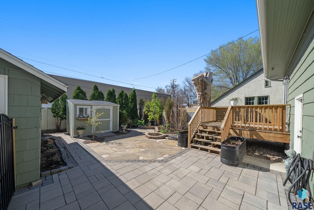view of patio featuring a deck, an outbuilding, a shed, and a fenced backyard