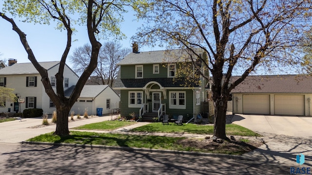 view of front of property with driveway, a chimney, and a garage