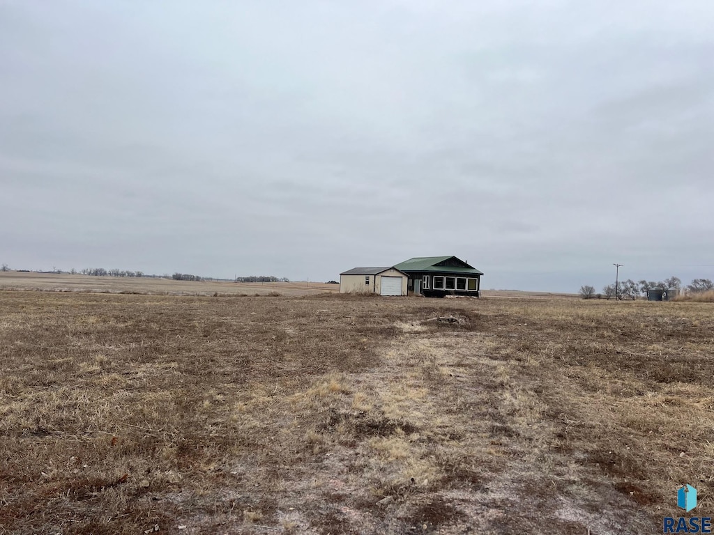 view of yard with a detached garage, an outdoor structure, and a rural view