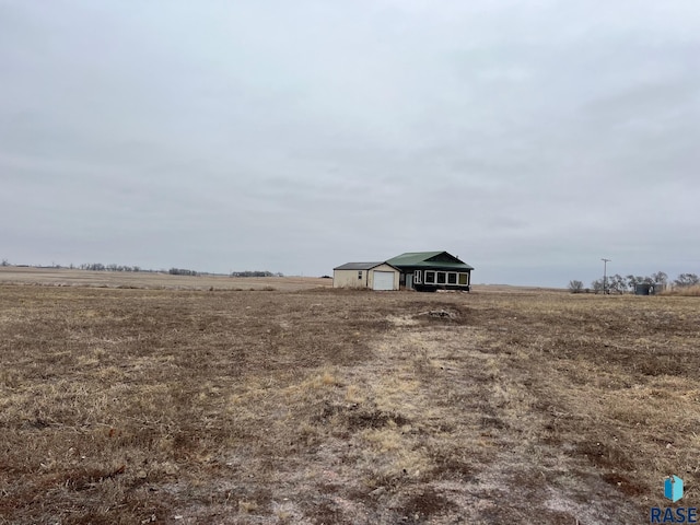 view of yard with a detached garage, an outdoor structure, and a rural view
