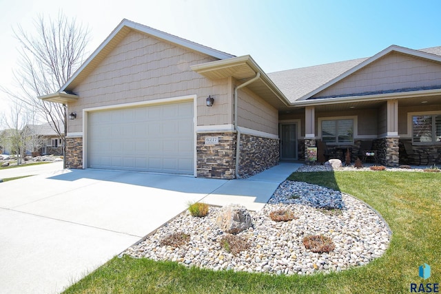 craftsman-style house with an attached garage, stone siding, and concrete driveway