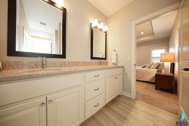 ensuite bathroom with double vanity, visible vents, a sink, baseboards, and ensuite bathroom