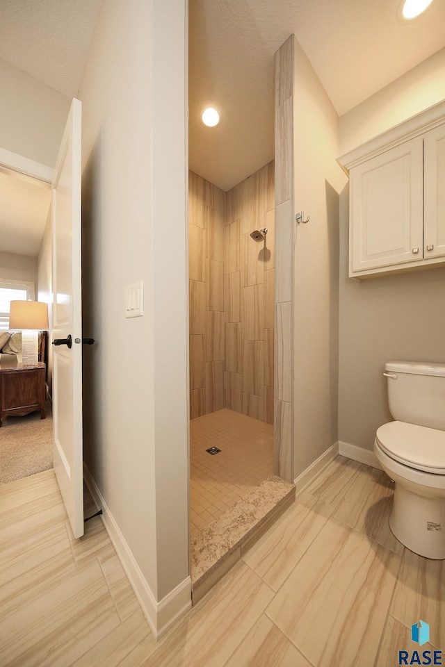 ensuite bathroom with baseboards, toilet, ensuite bathroom, recessed lighting, and tiled shower