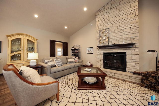 living room with high vaulted ceiling, a stone fireplace, recessed lighting, and wood finished floors