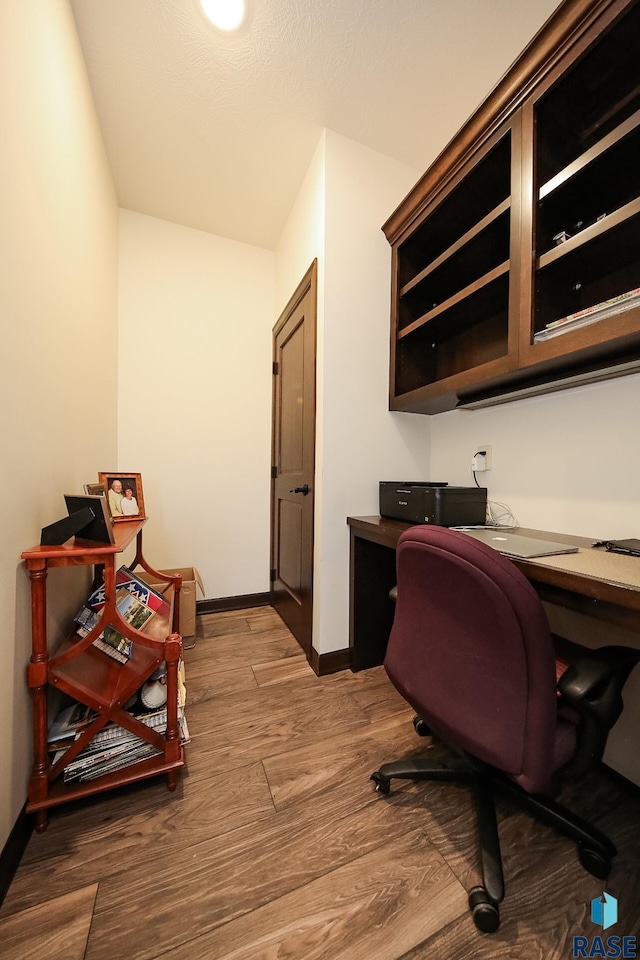 office space with built in study area, baseboards, and wood finished floors