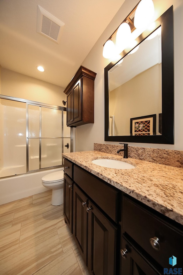 full bath with visible vents, vanity, toilet, recessed lighting, and bath / shower combo with glass door
