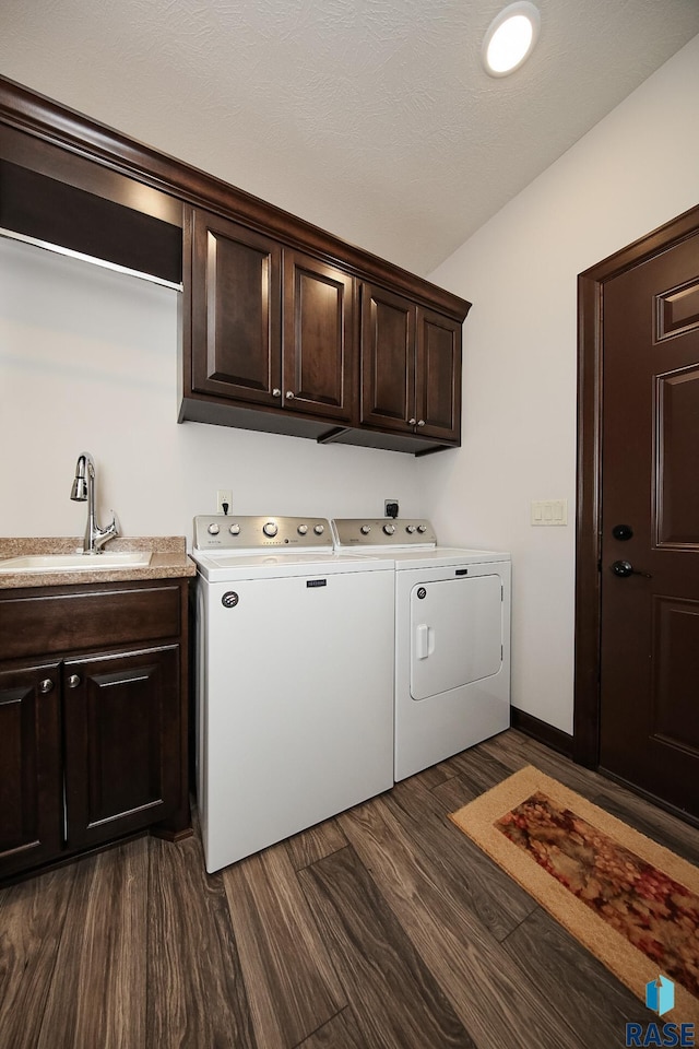 laundry area featuring a sink, cabinet space, dark wood-style flooring, and washing machine and dryer