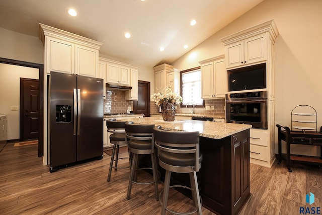 kitchen featuring dark wood-type flooring, a center island, cream cabinetry, backsplash, and stainless steel appliances