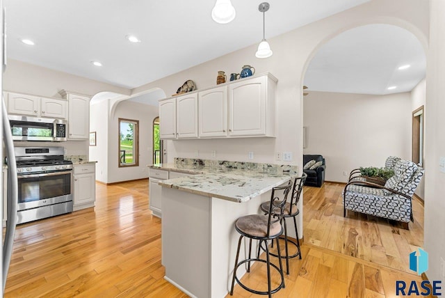 47604 255th St, Garretson, SD 57030 - kitchen featuring appliances with stainless steel finishes, arched walkways, white cabinetry, a peninsula, and a kitchen bar
