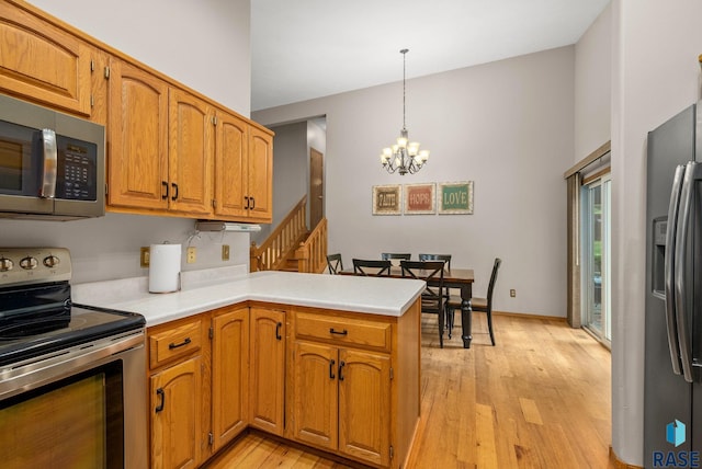 5215 E Belmont St, Sioux Falls, SD 57110 - kitchen with a peninsula, light countertops, a chandelier, light wood finished floors, and stainless steel appliances