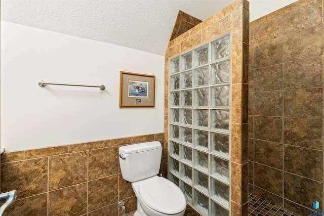 1705 N Deer Hollow Cir, Sioux Falls, SD 57110 - bathroom featuring a textured ceiling, tile walls, wainscoting, a walk in shower, and toilet