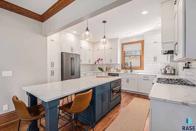 kitchen featuring a kitchen breakfast bar, wood finished floors, a sink, white cabinets, and stainless steel appliances