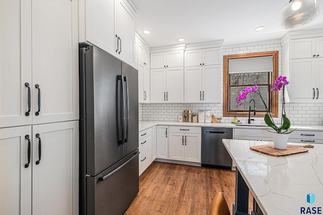 kitchen with appliances with stainless steel finishes, decorative backsplash, wood finished floors, and white cabinetry