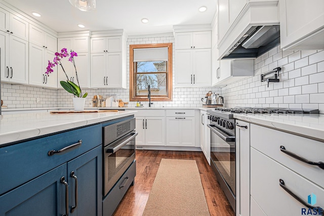 kitchen featuring blue cabinets, a sink, white cabinets, and stainless steel appliances