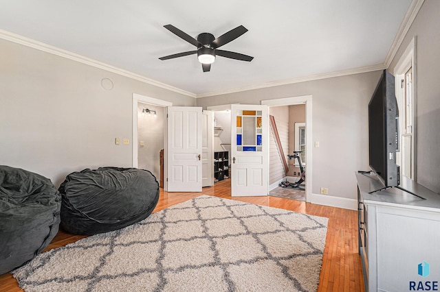bedroom with light wood-type flooring, a ceiling fan, baseboards, and crown molding