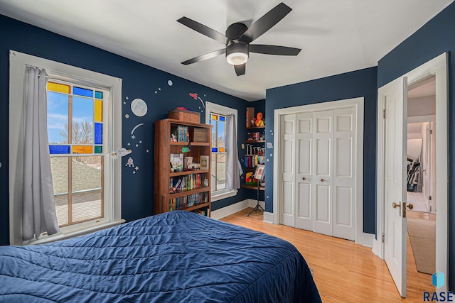 bedroom featuring baseboards, multiple windows, a ceiling fan, and light wood-type flooring