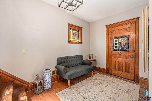 living area featuring an inviting chandelier, baseboards, light wood-type flooring, and visible vents