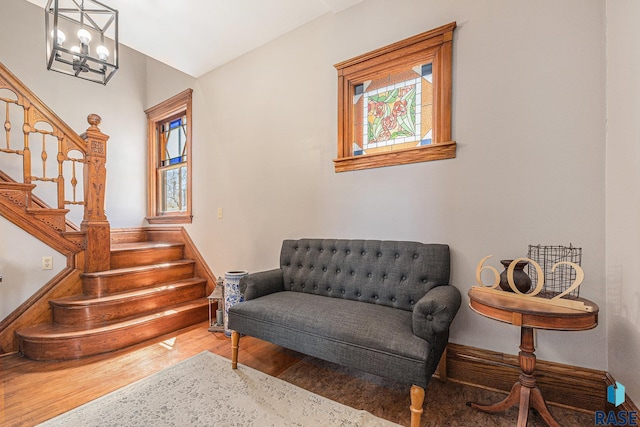 living area with stairway, wood finished floors, and a chandelier
