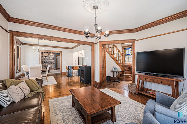 living room with crown molding, an inviting chandelier, stairs, baseboards, and dark wood-type flooring