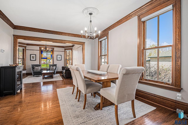dining room featuring ornamental molding, wood finished floors, and a chandelier