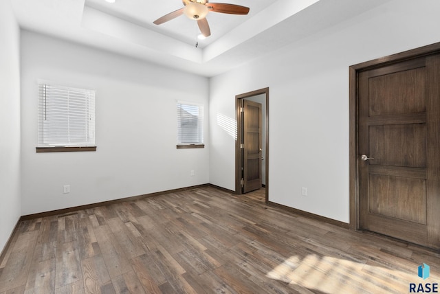5400 S Whisper Cove Trl, Sioux Falls, SD 57108 - unfurnished bedroom featuring baseboards, a ceiling fan, wood finished floors, and a tray ceiling