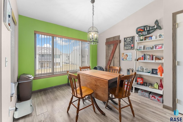 dining space featuring baseboards, a chandelier, wood finished floors, and vaulted ceiling