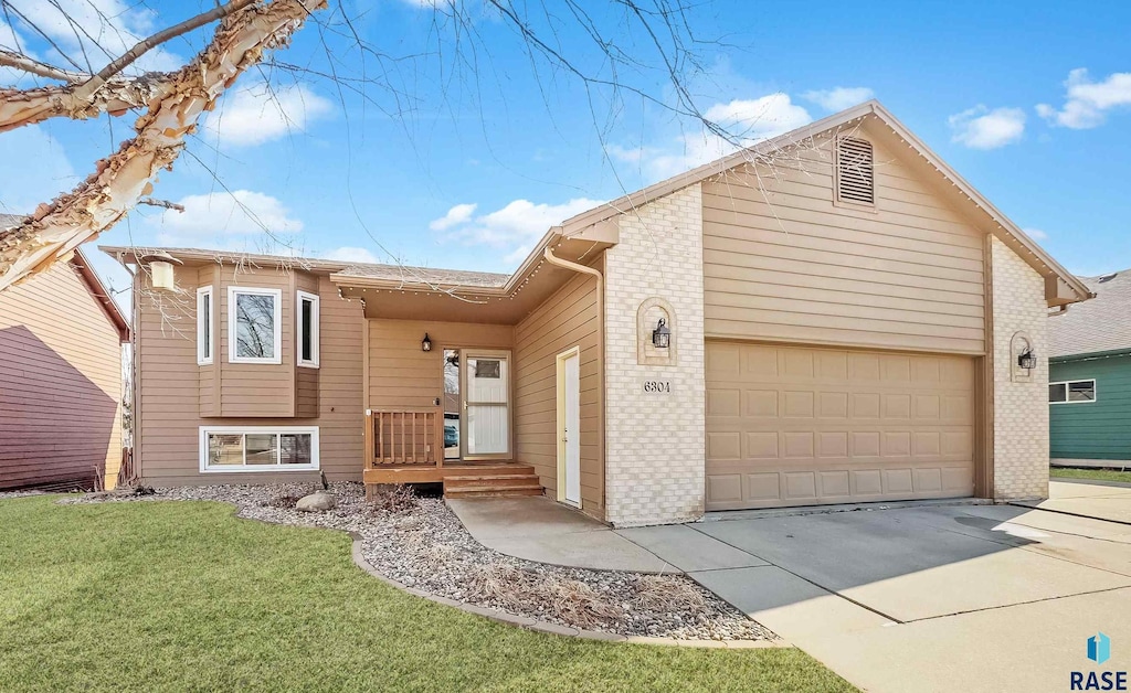 6304 S Mogen Ave, Sioux Falls, SD 57108 - view of front of house featuring brick siding, an attached garage, driveway, and a front lawn