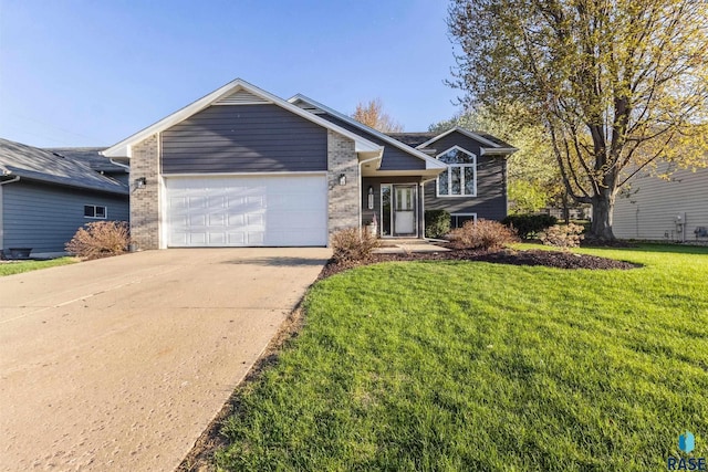split level home with a garage, concrete driveway, a front lawn, and brick siding