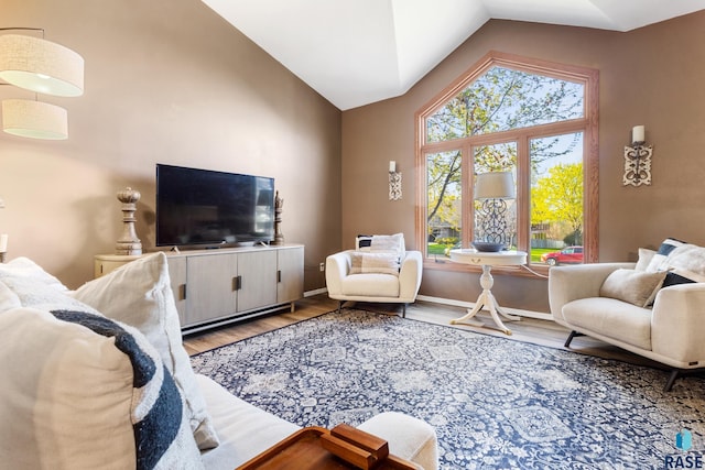 living area with baseboards, high vaulted ceiling, and wood finished floors