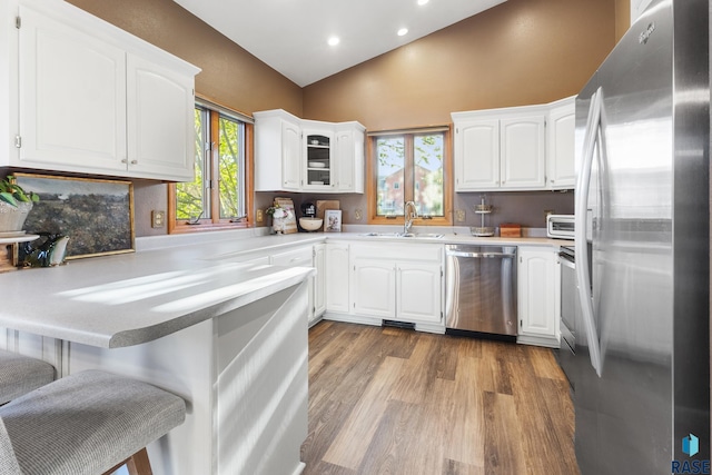 kitchen with a kitchen bar, wood finished floors, a sink, a peninsula, and stainless steel appliances