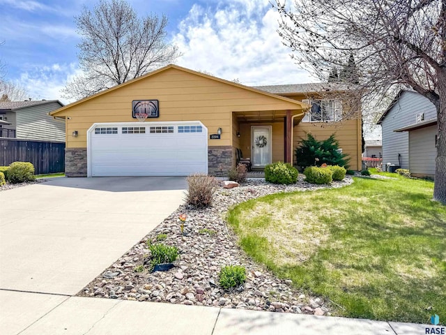 ranch-style home featuring a front yard, fence, concrete driveway, an attached garage, and stone siding