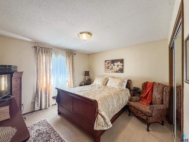 bedroom with a textured ceiling, light carpet, and a closet