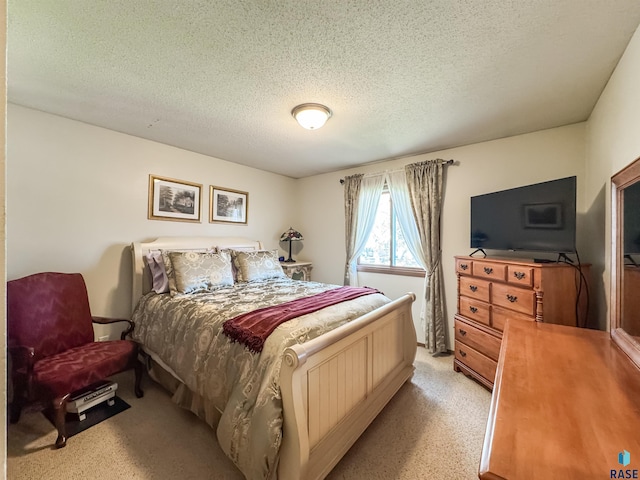 bedroom with a textured ceiling and light carpet