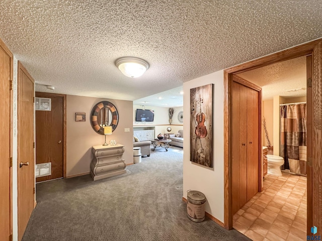 hallway featuring carpet floors, a textured ceiling, and baseboards
