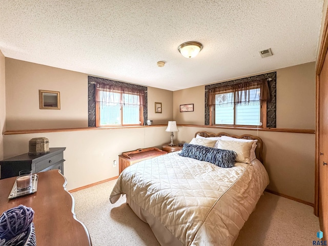 bedroom with multiple windows, carpet, a textured ceiling, and visible vents
