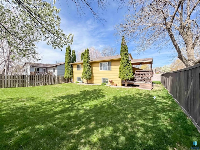 rear view of property featuring a fenced backyard, a wooden deck, and a lawn