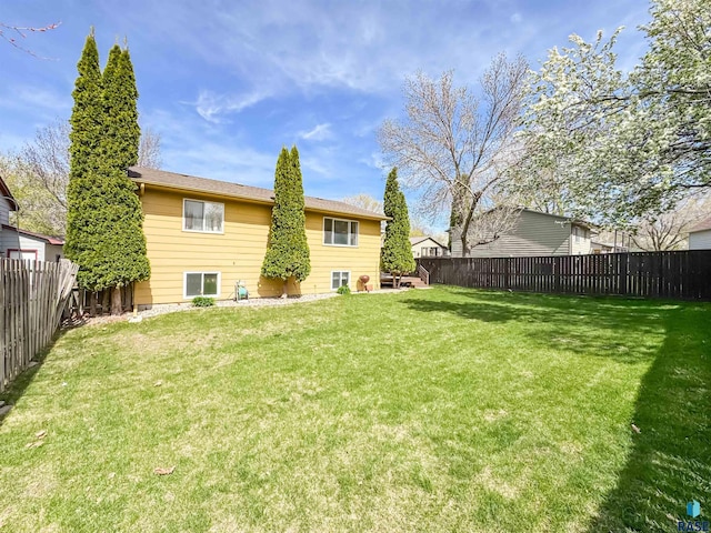 rear view of house with a lawn and a fenced backyard