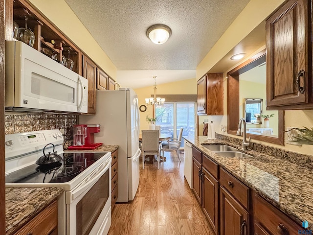 kitchen with an inviting chandelier, white appliances, light wood-style floors, a textured ceiling, and a sink