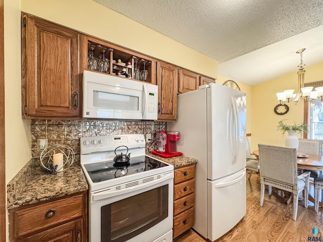 kitchen with decorative backsplash, brown cabinetry, light wood finished floors, a chandelier, and white appliances