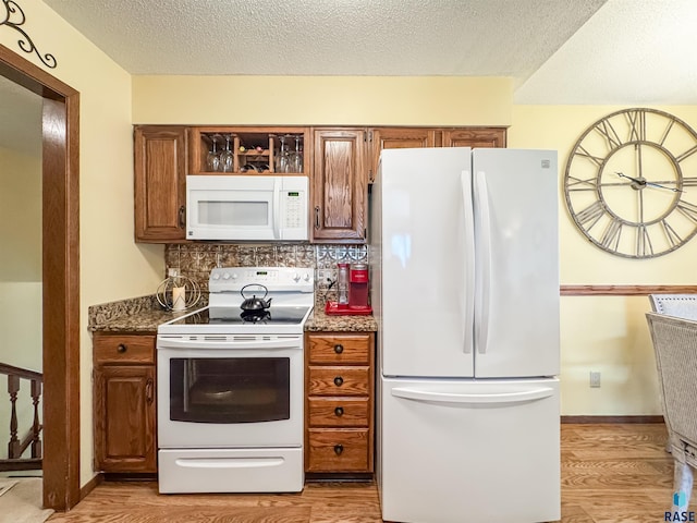 kitchen featuring light wood-style flooring, brown cabinets, and white appliances