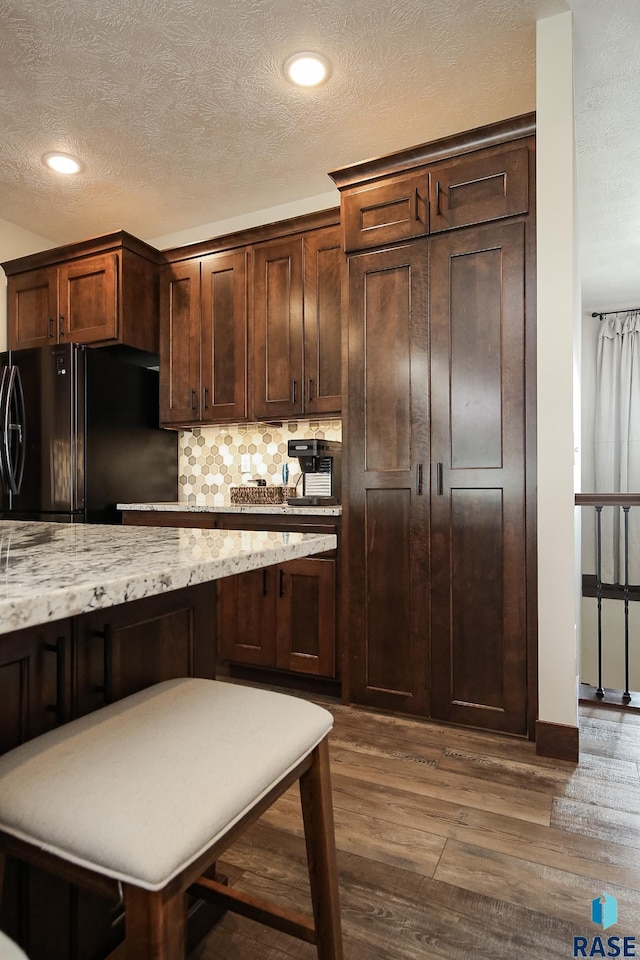 kitchen featuring a textured ceiling, freestanding refrigerator, recessed lighting, backsplash, and dark wood-style floors