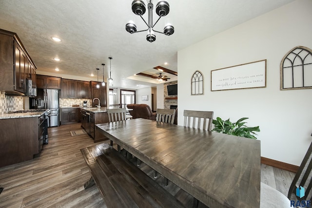 dining room featuring a fireplace, baseboards, dark wood-style floors, recessed lighting, and ceiling fan with notable chandelier