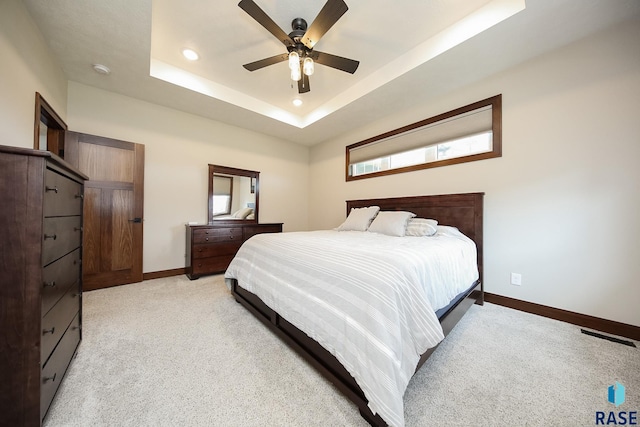 bedroom featuring ceiling fan, light carpet, a raised ceiling, recessed lighting, and baseboards